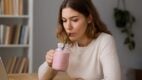 Žena pije smoothie za radnim stolom