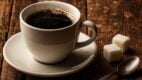 Šolja kafe sa šećerom i kašičicom na starom drvenom stolu.