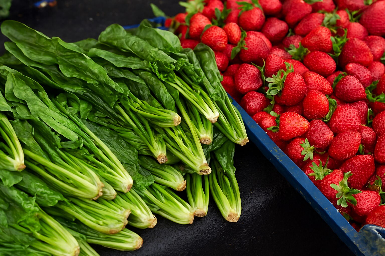 Najopasnije povrće na pijaci — svež spanać pored jagoda na tezgama.